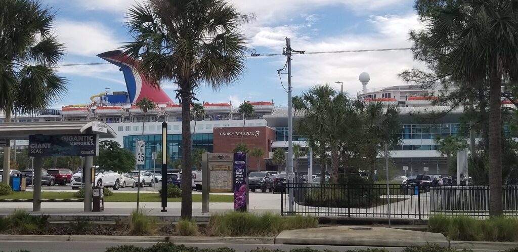 Port Tampa Bay: edificio de la Terminal de Cruceros 3 visto desde Channelside Drive, con palmeras delante y la chimenea roja y azul de un crucero detrás
