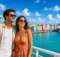 Pareja en la cubierta frente a un puerto con casas de colores y un crucero