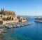Bahía mediterránea con catedral gótica y casco antiguo junto al mar, puerto deportivo y un barco crucero blanco