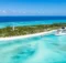 Vista aérea de una isla de Bahamas con playa blanca, faro y un barco crucero blanco en el muelle
