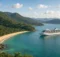 Barco crucero blanco anclado en una bahía de Brasil con playa dorada y cerros de selva verde