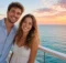 Pareja descansando en sillas de la terraza de un crucero mientras mira el atardecer sobre el mar