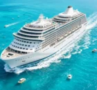 Gran barco crucero blanco navegando en mar turquesa rodeado de pequeñas embarcaciones en un día soleado