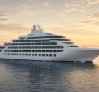 Barco crucero moderno blanco navegando en mar en calma al atardecer dorado