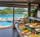 Bufé de frutas tropicales y jugos en la cubierta de un crucero frente a una playa del Caribe