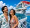 Pareja riendo en la cubierta de un crucero con toboganes rojos y el mar detrás