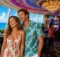 Pareja riendo en el casino de un crucero con máquinas de juego y ventanales al mar
